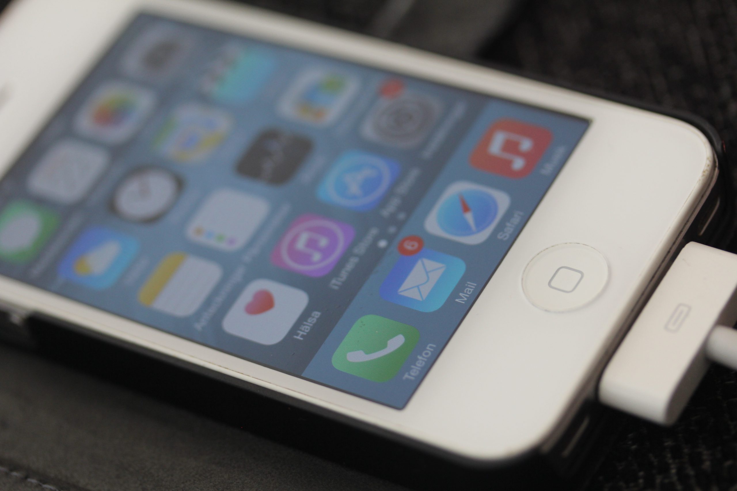 Bilden visar en iPhone på laddning, med app-ikonerna synliga. 